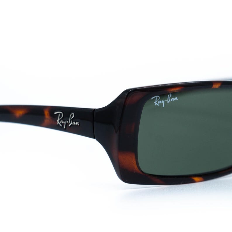 Puede incluir: Primer plano de gafas de sol Ray-Ban con montura carey y lentes verdes. El logotipo de Ray-Ban es visible en la patilla y la lente. Las gafas de sol tienen forma rectangular.
