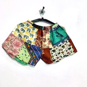 Könnte beinhalten: Eine Patchwork-Shorts bestehend aus verschiedenen Stoffbahnen mit unterschiedlichen Mustern, darunter gelbe Elefanten auf weißem Grund, florale Motive, geometrische Bordüren und einfarbige braune Abschnitte mit einem elastischen Bund.