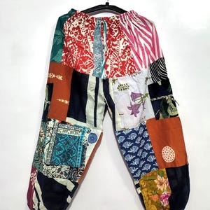 Puede incluir: Pantalones de patchwork que presentan una variedad de paneles de tela coloridos con diversos patrones, incluyendo diseños florales, de rayas y geométricos. Los pantalones tienen una cintura elástica con cordón y puños elásticos en las piernas.