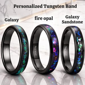 Könnte beinhalten: Drei schwarze Wolframringe mit der Aufschrift Personalized Tungsten Band. Die Ringe haben Einlagen aus Galaxy, fire opal und Galaxy Sandstone. Jeder Ring trägt die Gravur Soul Mate auf der Innenseite und zeigt bunte, zerkleinerte Steinmuster.