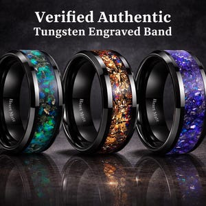 Könnte beinhalten: Drei schwarze Wolframringe mit dem Text Verified Authentic Tungsten Engraved Band darüber. Jeder Ring hat eine mittige Einlage aus zerkleinertem Material in Grün, Orange oder Blau. Die Innenseite ist mit Heart Mate graviert.