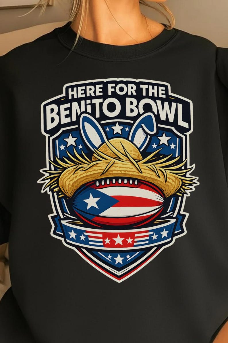 May include: Black sweatshirt with a graphic of a football wearing a straw hat and bunny ears. The football has the Puerto Rican flag design. The text reads "HERE FOR THE BENITO BOWL" in white and blue.
