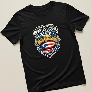 May include: Black t-shirt with a graphic featuring a football wearing a straw hat and bunny ears, with the text "HERE FOR THE BENITO BOWL". The design incorporates the Puerto Rican flag and stars.