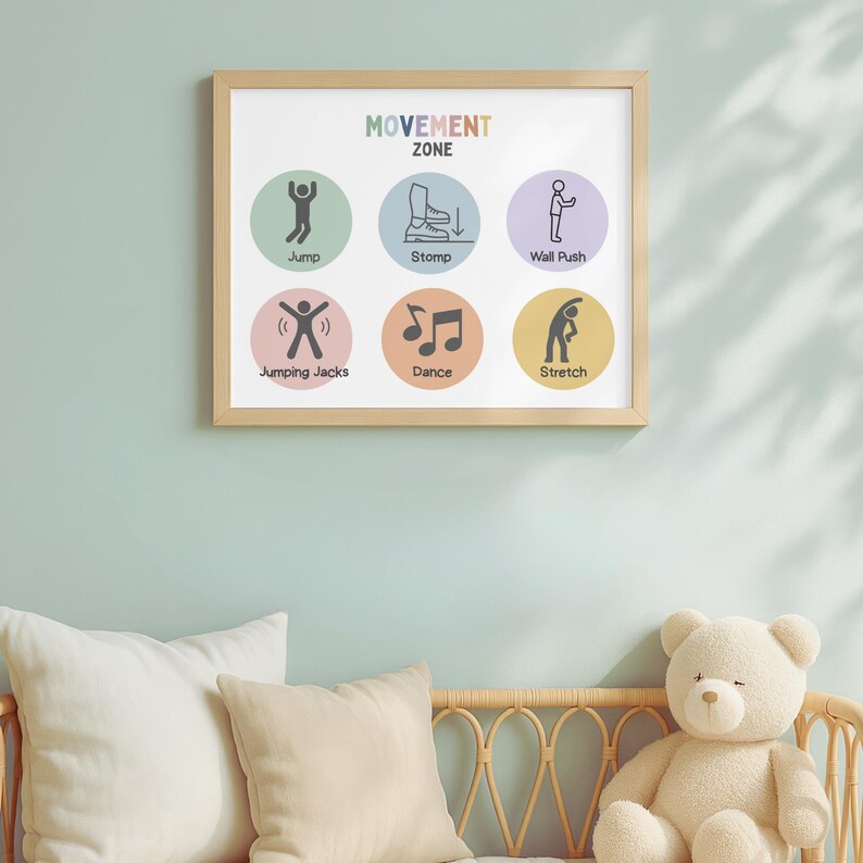 May include: A framed print titled "MOVEMENT ZONE" with colorful circles illustrating various activities: Jump, Stomp, Wall Push, Jumping Jacks, Dance, and Stretch. The print is in a light wood frame, hanging on a light blue wall above pillows and a teddy bear.