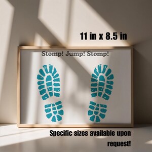 May include: Framed artwork with a white background featuring two turquoise footprints and the text "Stomp! Jump! Stomp!". The frame measures 11 inches by 8.5 inches. Additional sizes are available upon request.