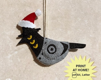 May include: A handmade felt Christmas decoration in the shape of a bird, wearing a Santa hat. The bird is black and grey with yellow details. The decoration hangs from a string. Text on the image says "PRINT AT HOME! pdf A4, Letter".