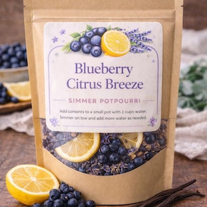 May include: A brown paper bag of "Blueberry Citrus Breeze" simmer potpourri. The bag features a label with blueberries, lemon slices, and lavender. Fresh blueberries, lemon slices, and vanilla beans are arranged around the bag.