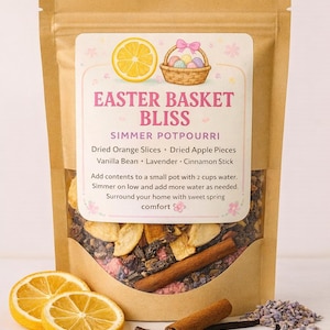 May include: A brown paper bag of Easter Basket Bliss simmer potpourri. The label features a lemon slice and an Easter basket illustration. Ingredients include dried orange slices, apple pieces, vanilla bean, lavender, and a cinnamon stick. Two lemon slices and a cinnamon stick are visible.