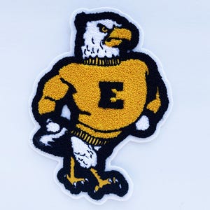 May include: Embroidered patch featuring a stylized eagle mascot in a yellow sweater with a black outline. The eagle has a white head and chest, a yellow beak, and black accents. The letter "E" is prominently displayed on the sweater.