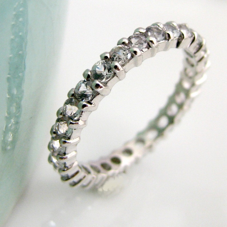 May include: A silver band ring with a row of clear cubic zirconia stones.