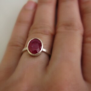 K&ouml;nnte beinhalten: Ein silberner Ring mit einem roten ovalen Edelstein.