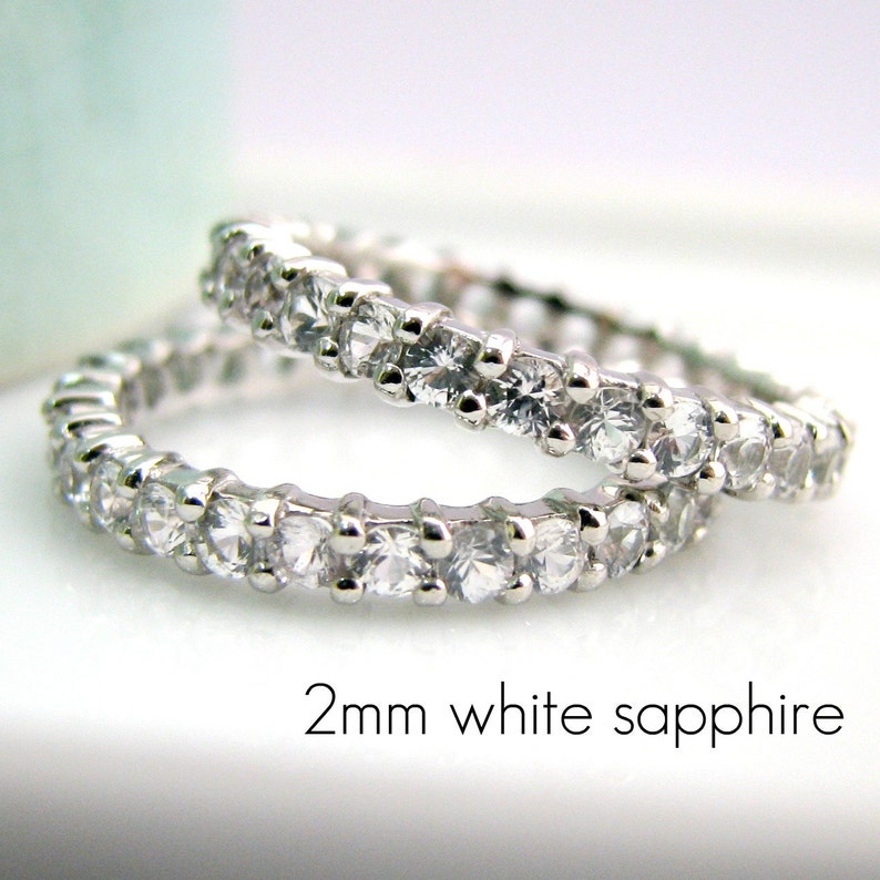 May include: Two silver eternity bands set with a row of 2mm white sapphires.