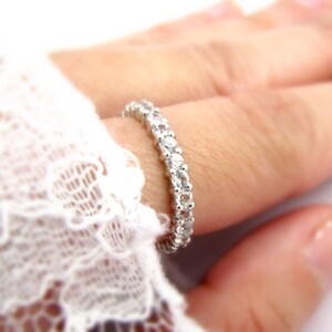 May include: A silver band ring with a row of small, clear gemstones.
