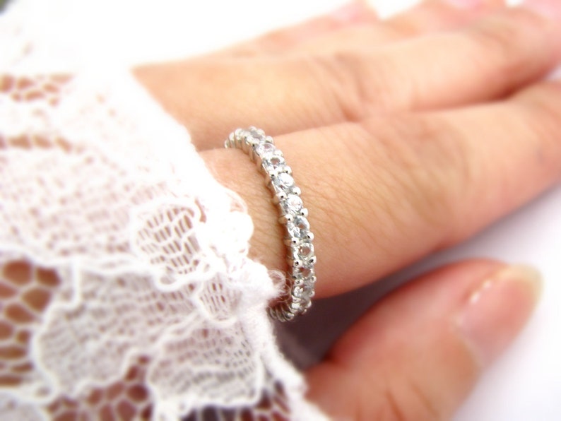 May include: A silver band ring with a row of small, clear gemstones.