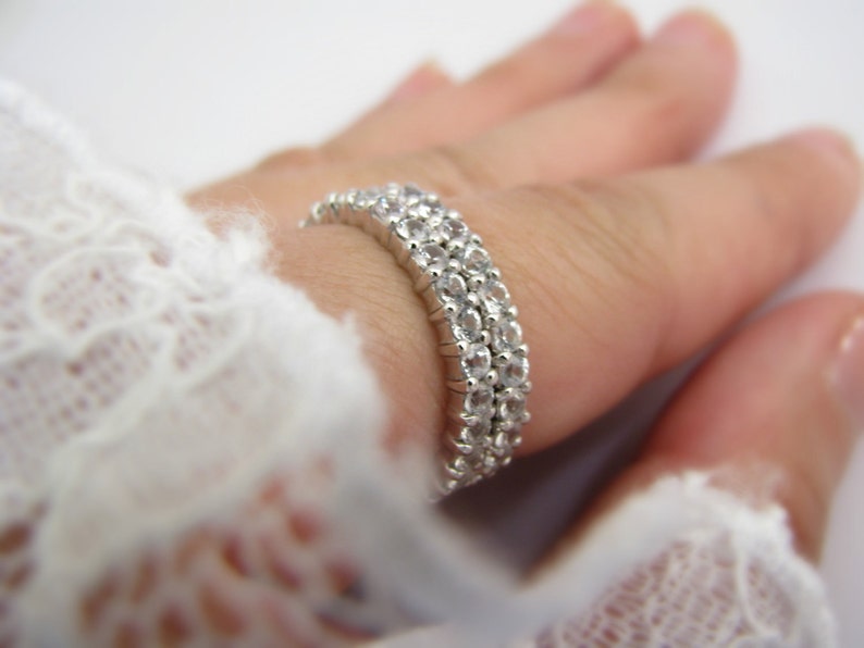 May include: A silver ring with three rows of clear cubic zirconia stones.