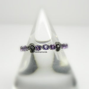 May include: A silver band ring with a row of purple gemstones and skull accents.