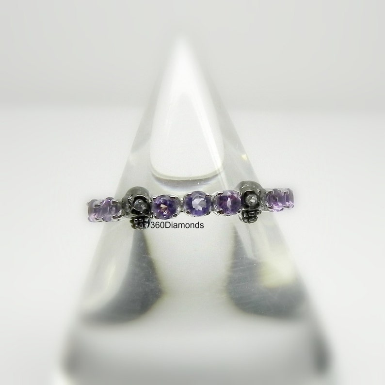 May include: A silver band ring with a row of purple gemstones and skull accents.