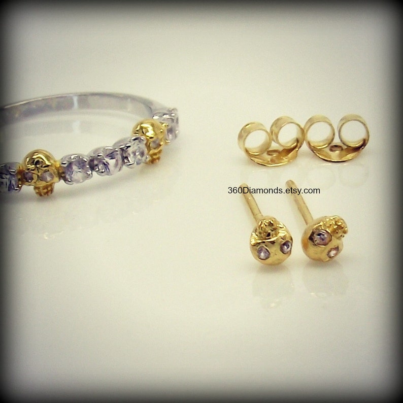 May include: A set of gold skull earrings with small clear stones. The earrings are on a white surface. 360Diamonds.etsy.com