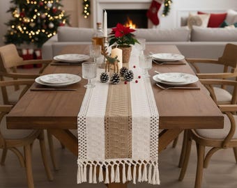 May include: A wooden dining table set for a holiday meal. The table is adorned with a white and tan table runner with fringe, plates, glasses, candles, pinecones, and a poinsettia. A Christmas tree and fireplace are visible in the background.