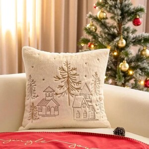 Pu&ograve; includere: Cuscino decorativo color crema con scena di villaggio invernale ricamata. Il cuscino presenta una superficie morbida e strutturata e un design dettagliato di case e alberi nei toni del marrone. Un accento accogliente per l'arredamento festivo.