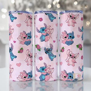 Peut inclure: Trois gobelets en acier inoxydable avec un fond rose et un motif r&eacute;p&eacute;t&eacute; de personnages de dessins anim&eacute;s bleus et roses, de c&oelig;urs et de fleurs. Les gobelets sont cylindriques et ont un bord argent&eacute;.