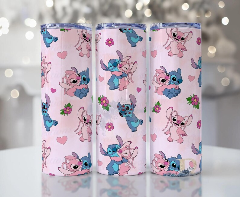 Peut inclure: Trois gobelets en acier inoxydable avec un fond rose et un motif r&eacute;p&eacute;t&eacute; de personnages de dessins anim&eacute;s bleus et roses, de c&oelig;urs et de fleurs. Les gobelets sont cylindriques et ont un bord argent&eacute;.