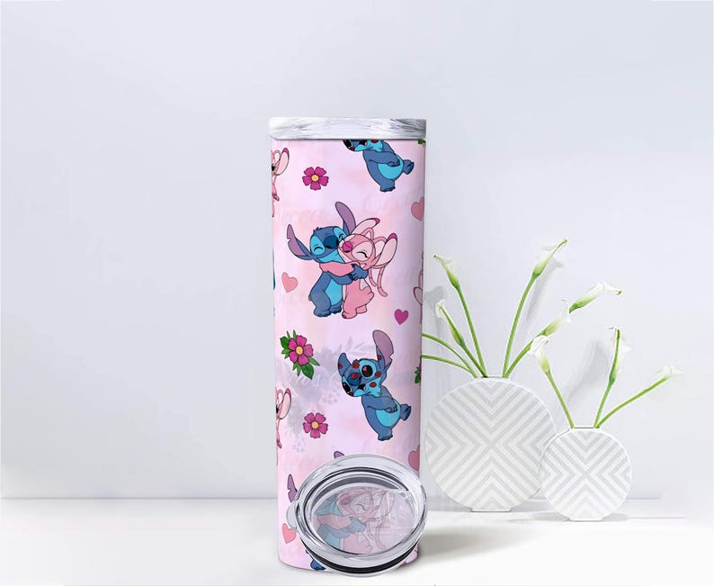 Peut inclure: Un gobelet rose avec un motif r&eacute;p&eacute;t&eacute; de personnages de dessins anim&eacute;s bleus et roses, avec des c&oelig;urs et des fleurs. Le gobelet a un couvercle argent&eacute; et un fond transparent. Le design est fantaisiste et color&eacute;. Le gobelet est de forme cylindrique.