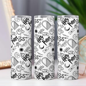 May include: Three white Harry Potter themed tumblers with a black and white pattern. The pattern includes the words "Harry Potter", lightning bolts, and other iconic symbols. The tumblers are cylindrical and appear to be made of stainless steel.