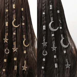 Könnte beinhalten: Nahaufnahme von dunkelbraunem, geflochtenem Haar, das mit goldenen und silbernen Haaraccessoires verziert ist. Die Accessoires umfassen Stern- und Halbmond-Anhänger sowie dekorative Perlen. Die Haaraccessoires verleihen einen Bohemian-Flair.