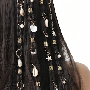 May include: Dark brown braided hair decorated with gold hair rings, beads, and charms. Charms include pearls, seashells, and starfish. These hair accessories add a bohemian style to the hairstyle.