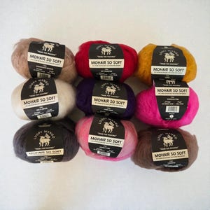 May include: Nine skeins of Loopy Mango Mohair So Soft yarn in various colors, including brown, red, yellow, white, purple, pink, and dark grey. Each skein has a black label with white text.