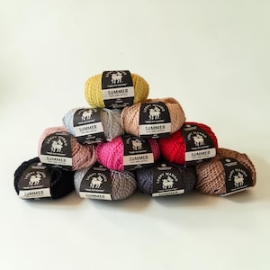 May include: A pyramid stack of ten balls of Loopy Mango Summer 100% pure cotton yarn in various colors including yellow, light blue, pink, red, black, grey, and brown. Each ball features a black paper label with a white sheep logo and text.