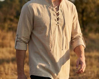 Può includere: Camicia di lino beige con colletto alla coreana e allacciatura frontale. Le maniche lunghe sono arrotolate. La camicia è realizzata in tessuto leggero, adatta per il clima caldo. La camicia è in stile casual.