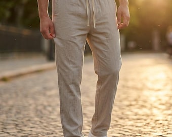 Può includere: Pantaloni in lino beige con vita con coulisse e tasche laterali. I pantaloni sono abbinati a scarpe da ginnastica bianche. Il tessuto ha un aspetto strutturato. I pantaloni sono di colore neutro.