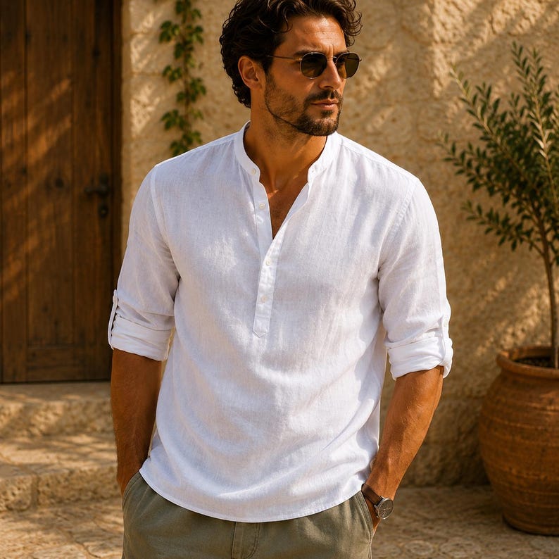 Pode incluir: Uma camisa branca de manga comprida com gola mandarim e carcela de bot&otilde;es parcial. A camisa apresenta mangas dobradas, um acabamento de tecido texturizado e um corte relaxado com um decote simples e linhas limpas.