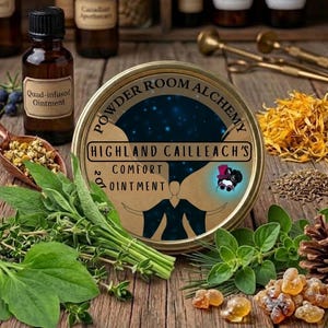 Könnte beinhalten: Eine runde goldene Dose mit der Aufschrift Powder Room Alchemy Highland Cailleach's Comfort Ointment, einem dunkelblauen Sternenhintergrund und einer Figurenillustration, umgeben von frischen grünen Kräutern, Trockenblumen, Harz und einer Braunglasflasche.