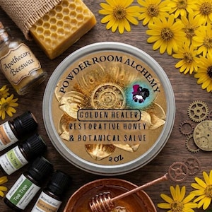Puede incluir: Una lata metálica redonda etiquetada como Powder Room Alchemy Golden Healer Restorative Honey & Botanical Salve 2 oz, rodeada de flores amarillas, frascos de aceites esenciales, un bloque de panal y engranajes decorativos.