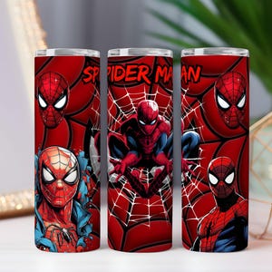 May include: Three red tumblers with Spider-Man designs. The tumblers show different images of Spider-Man, including his face and full body, set against a red background with spiderwebs. The text "SPIDER MAN" is visible on one tumbler.