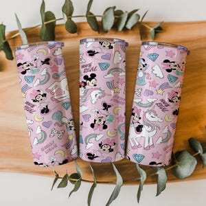 May include: Three pink insulated tumblers with a repeating pattern of Minnie Mouse, rainbows, unicorns, and diamonds. The tumblers have a silver lid and the text "100% REAL" and "Unicorn Dreams".