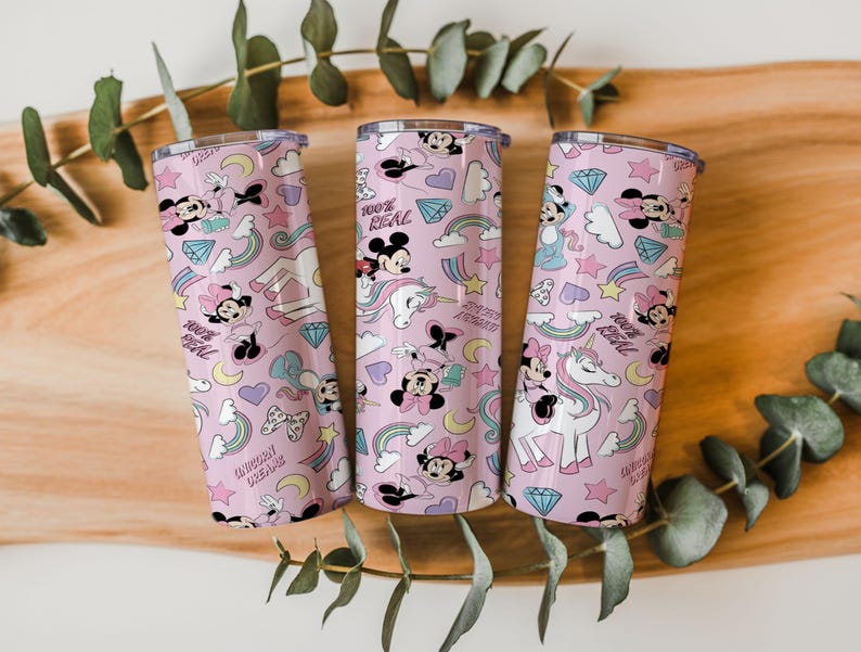 May include: Three pink insulated tumblers with a repeating pattern of Minnie Mouse, rainbows, unicorns, and diamonds. The tumblers have a silver lid and the text "100% REAL" and "Unicorn Dreams".