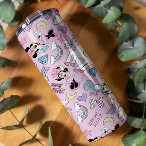 May include: A pink tumbler with a repeating pattern of Minnie Mouse, rainbows, diamonds, stars, and unicorns. The text "100% REAL" and "UNICORN DREAMS" are also featured on the tumbler. The tumbler has a silver lid.