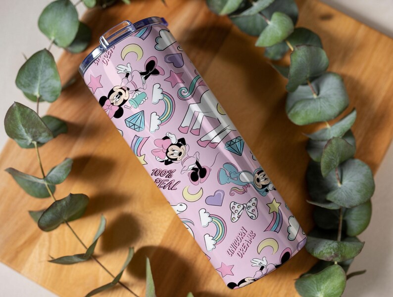 May include: A pink tumbler with a repeating pattern of Minnie Mouse, rainbows, diamonds, stars, and unicorns. The text "100% REAL" and "UNICORN DREAMS" are also featured on the tumbler. The tumbler has a silver lid.
