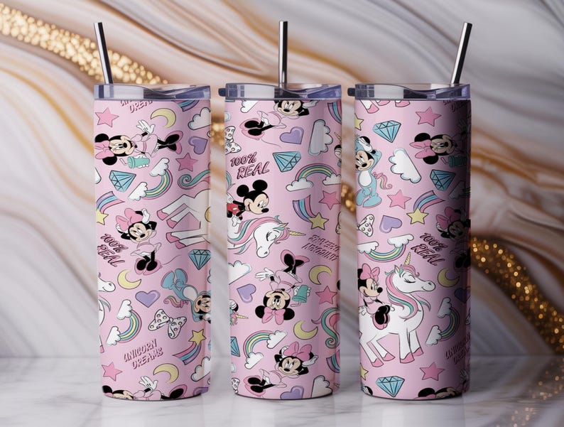 May include: Three pink insulated tumblers with a repeating pattern of Minnie Mouse, Mickey Mouse, rainbows, unicorns, and diamonds. Each tumbler has a silver straw and a lid. The text "100% REAL" and "UNICORN DREAMS" are also visible.