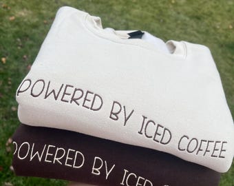 Moletom Gildan com gola redonda e bordado "Powered By Coffee", ideal para amantes de café, fabricado nos EUA.