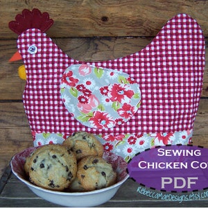 Puede incluir: Un guante de horno con forma de pollo de cuadros rojos y blancos con un estampado floral en la parte posterior. El guante de horno está sobre una superficie de madera con un tazón de magdalenas delante. El texto "Sewing Chicken Cozy PDF" está en una pancarta morada.
