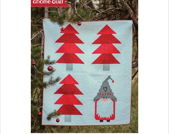 May include: A Scandinavian Tomte quilt pattern featuring a red and white design with four stylized Christmas trees and a gnome. The quilt measures 54 inches by 62 inches.