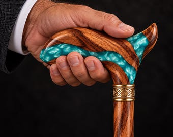 May include: A walking cane featuring a polished brown wood handle with a swirling turquoise resin inlay. The handle is connected to the wooden shaft by a decorative gold-colored metal collar with an intricate woven knot pattern.