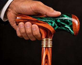 May include: A walking cane featuring a polished wood handle with a swirling emerald green resin inlay. The handle is connected to the shaft by a gold-colored metal collar with an intricate embossed Celtic knot pattern.