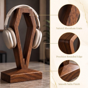 May include: A wooden headphone stand with a geometric, elongated hexagonal frame and a rectangular base. The stand features a natural Sheesham grain, precision rounded edges, and a smooth satin finish. Light-colored headphones rest on the stand.