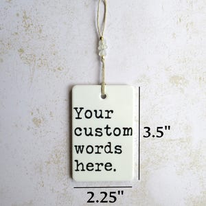 May include: A rectangular white ornament with the text "Your custom words here." It measures 3.5 inches tall and 2.25 inches wide. The ornament hangs from a string with beads.